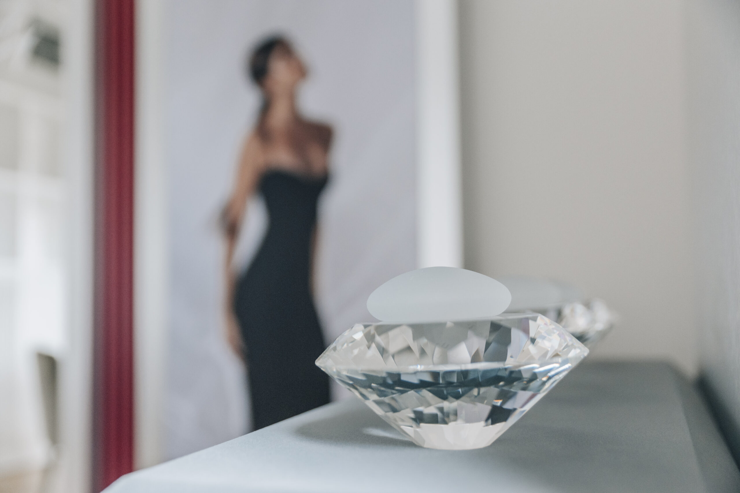 Brustimplantat auf Diamant, im Hintergrund Frau im Abendkleid